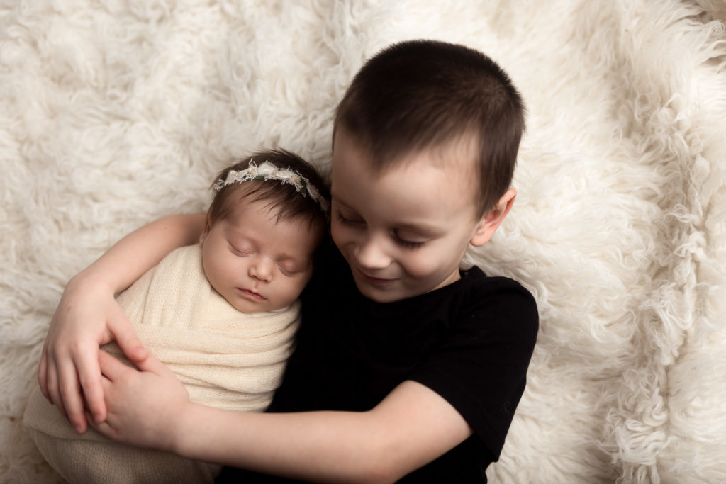 newborn baby girl with brother on flokati fur