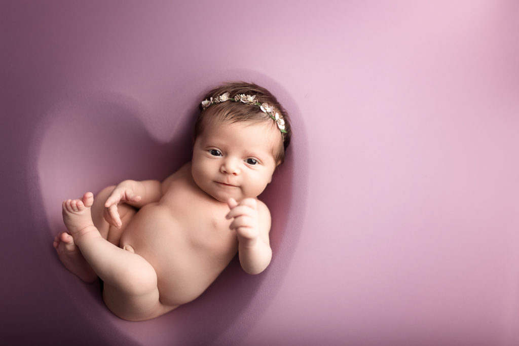 baby girl in purple heart bowl newborn photoshoot