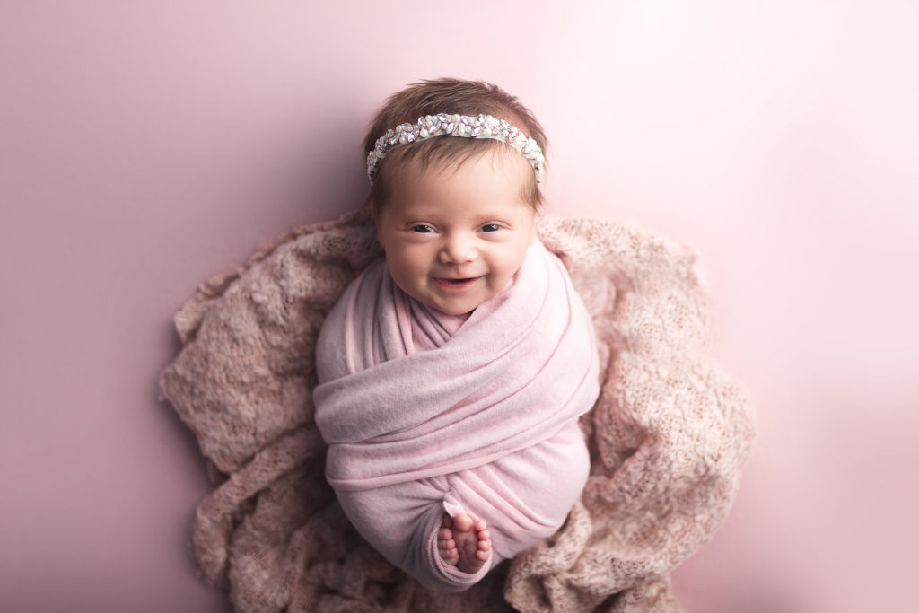 newborn baby girl smile on pink