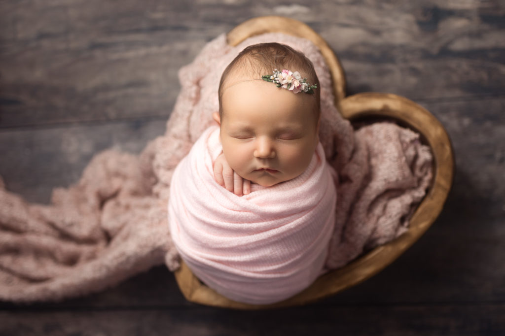 newborn baby in pink heart bowl 